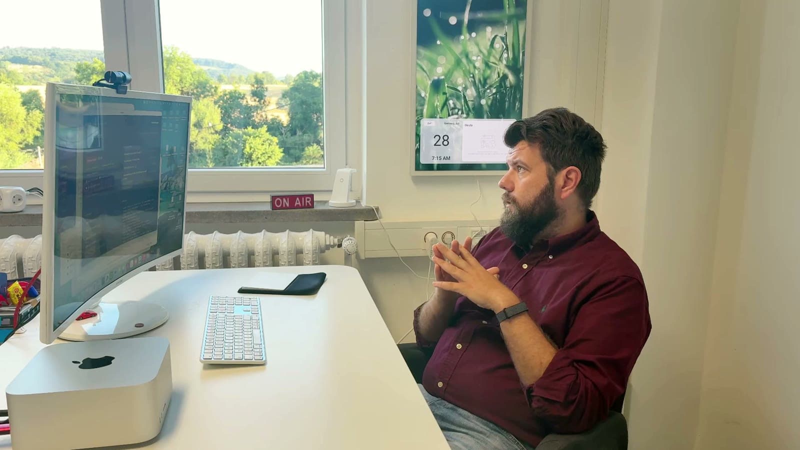 Philip Kleudgen an seinem Schreibtisch im Hotel, Blick auf den Monitor, daneben ein ON-AIR-Schild